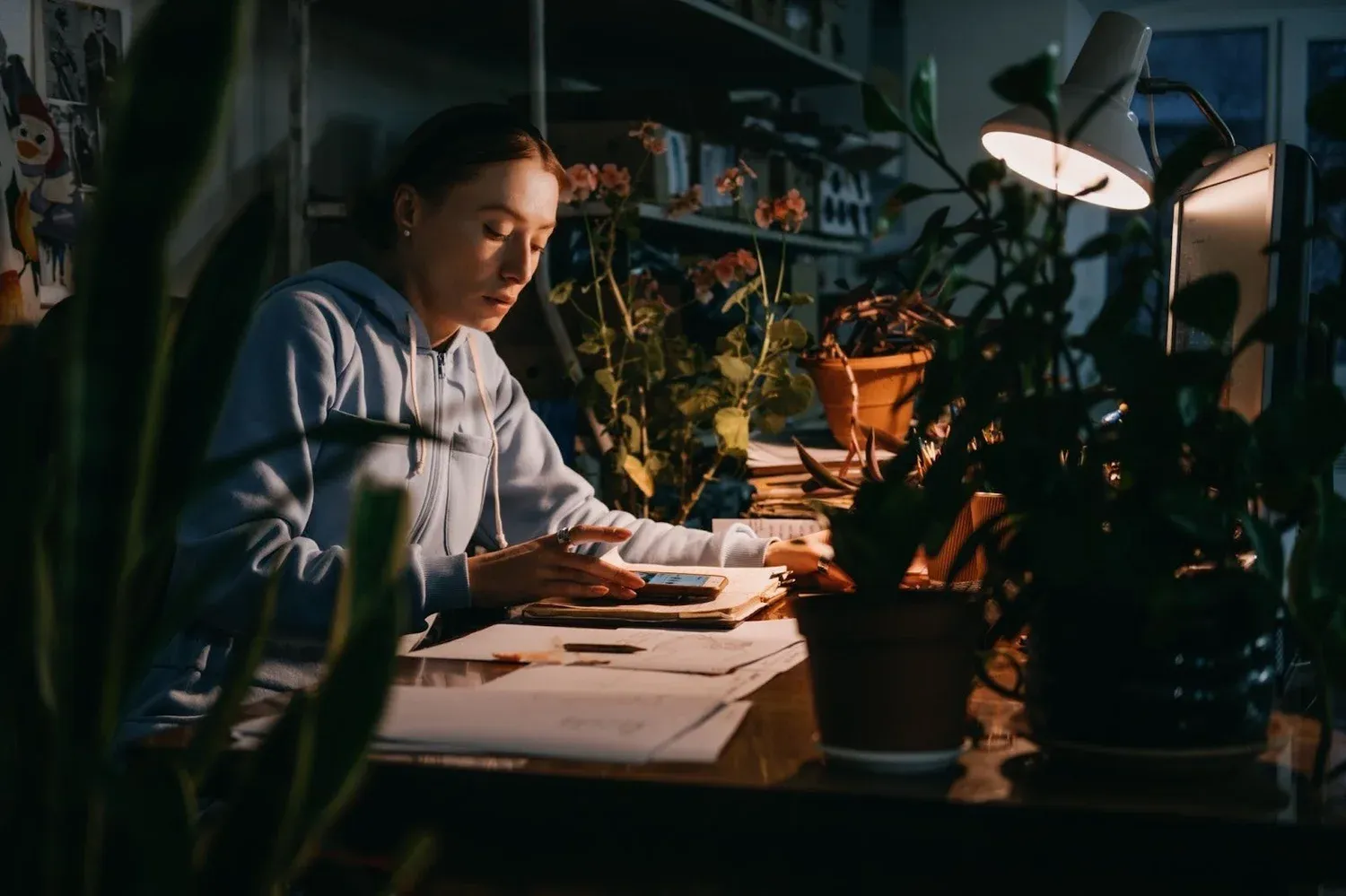 Woman reading notes at a desk lit by a lamp at night