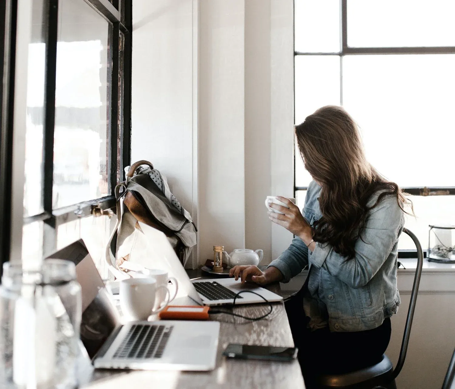 Woman working on a laptop at a café window table