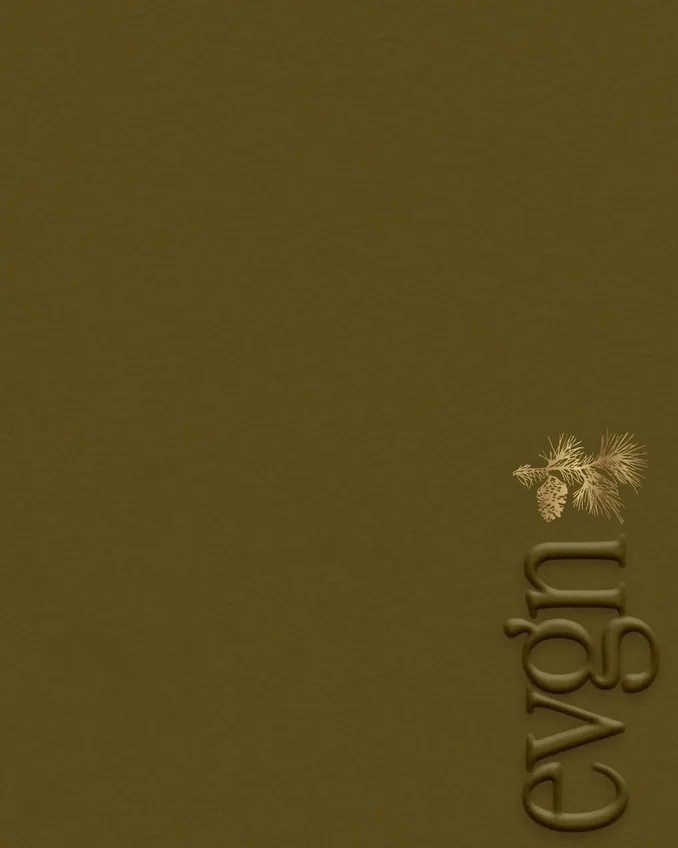 Close-up of a gold surface with embossed text ‘GARDEN’ and a decorative pine branch with pine cone in the corner.